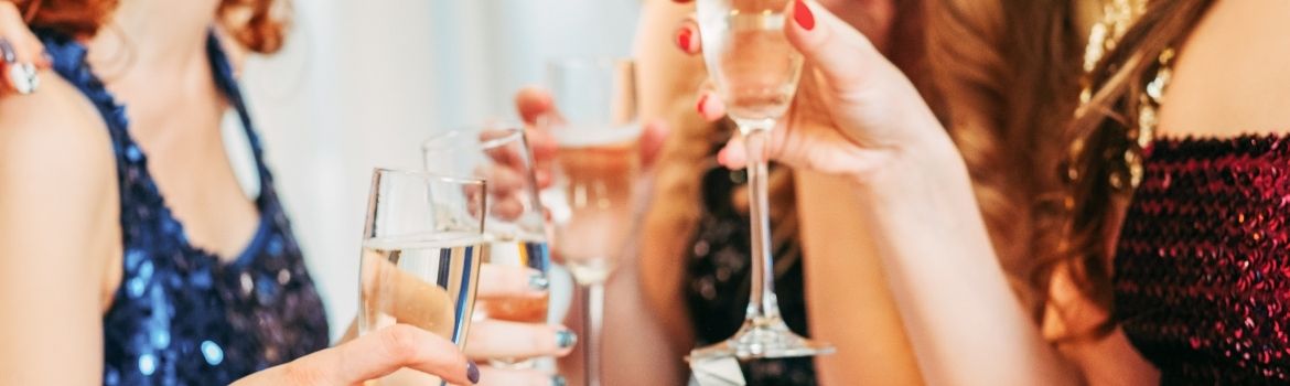 Ladies holding champagne glasses and gowns about to toast