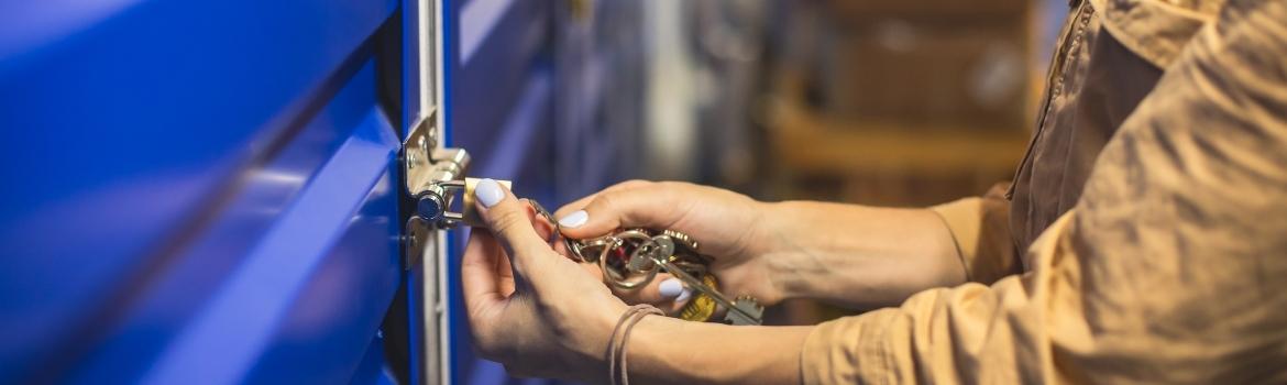 a person unlocking a small gold padlock with their ring of keys