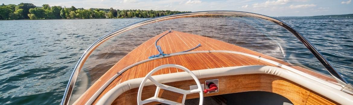 a speed boat with faux wood exterior on the lake surrounded by green trees