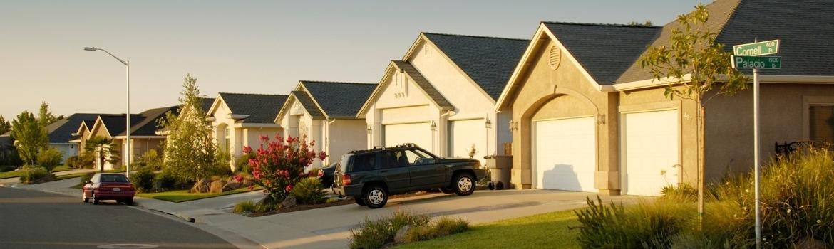 a tract home neighborhood consisting of single story homes on a curved street with an SUV in the driveway